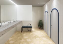 Publiczna toaleta ze ścianami wyłożonymi białymi płytkami Rim White Decor z dwoma parami drzwi, z wiszącą półką lastryko z umywalkami, niebieskim siedziskiem i kwiatem w donicy