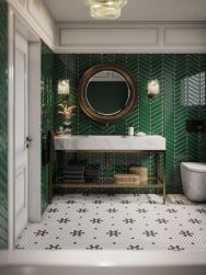 Łazienka ze ścianami wyłożonymi zieloną mozaiką Royal Chevron Vert z marmurową półką na stelażu, okrągłym lustrem, miską WC i białymi drzwiami