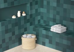 Pomieszczenie wyłożone zielonymi płytkami Rubik Green z koszem wiklinowym, ręcznikami i akcesoriami łazienkowymi
