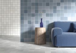 Pomieszczenie wyłożone kolorowymi płytkami z kolekcji Rubik z niebieską kanapą oraz stolikiem z niebieskim wazonem