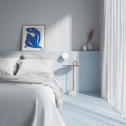 Sypialnia z podłogą i częścią ściany wyłożoną niebieskimi płytkami lastryko Sensa Blue, z łóżkiem z białą pościelą, oryginalnym stolikiem, kulistą lampą, ozdobami i obrazem