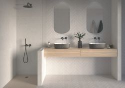 Łazienka ze ścianami pod prysznicem wyłożonym szarymi płytkami Sensa Silver, z wiszącą drewnianą półką z dwiema umywalkami nablatowymi i dwoma owalnymi lustrami