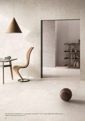 Pomieszczenie wyłożone jasnymi płytkami imitującymi beton z kolekcji Sixty ze stołem, oryginalnym krzesłem, piłką i lampą wiszącą