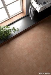 Podłoga wyłożona pomarańczowymi cegiełkami Stage Terracotta oraz wisząca umywalka lastryko
