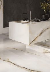 Podłoga w kuchni i wyspa wyłożone białymi płytkami imitującymi kamień onyks z kolekcji Tele di Marmo Pure Onyx