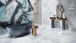 Elegancka łazienka wyłożona błękitnymi płytkami imitującymi kamień z kolekcji Tele di Marmo Precious z niebieską wanną, kabiną prysznciową, dwiema umyalkami stojącymi i owalnym lustrem