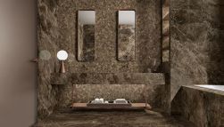 Ciemna, brązowa łazienka wyłożona płytkami imitującymi kamień z kolekcji Tele di Marmo z zabudowaną wanną, półką wiszącą z dwiema umywalkami i prostokątnymi lustrami oraz lampką stojącą