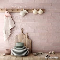 Różowa ściana w kuchni wyłożona cegiełkami z kolekcji Tribeca z drewnianym blatem, wieszakami, deskami i naczyniami