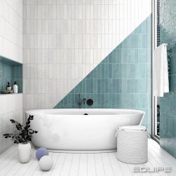 Łazienka utrzymana w biało-niebieskiej kolorystyce z białą wanną, ręcznikiem wiszącym na ścianie, koszem wiklinowym, kwiatem w dzbanie i półką w ścianie z kosmetykami