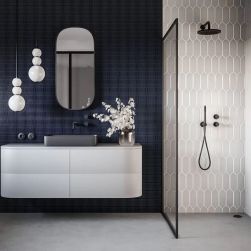 Łazienka ze ścianą pod prysznicem wyłożoną beżowymi płytkami Tritone Beige 01, a poza prysznicem z granatową ścianą, białą szafką wiszącą z umywalką nablatową, lustrem i lampami wiszącymi