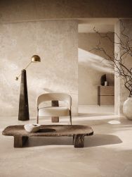 Pokój wyłożony beżowymi płytkami imitującymi kamień z kolekcji Unique Infinity, z fotelem, niskim stolikiem i lampą