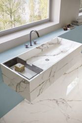 Umywalka i podłoga w łazience wyłożone jasnymi płytkami imitującymi marmur z kolekcji Unique Marble Marmo Paonazzetto