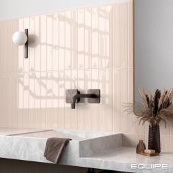 Ściana w łazience wyłożona beżowymi cegiełkami dekoracyjnymi w połysku Vitral Axis Sand, z szarym blatem z umywalką