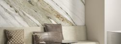 Ściana w pokoju wyłożona płytkami imitującymi marmur Marmi Maxfine Vogue z kanapą z poduszkami