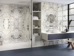 Łazienka wyłożona płytkami imitującymi marmur w połysku Mirror Alpen Quartz z kabiną prysznicową, wiszącą szafką z umywalką nablatową, okragłym lustrem i półkami