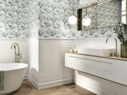 Elegancka łazienka wyłożona płytkami dekoracyjnymi z kolekcji Fables, z wanną wolnostojącą, wiszącą szafką z umywalką nablatową, lustrem i złotymi elementami