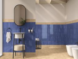 Łazienka wyłożona niebieskimi płytkami w połysku Fayenza Blue ze stojącą umywalką, owalnym lustrem oraz miską WC i bidetem