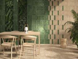 Pokój ze ścianą wyłożoną w części zielonymi cegiełkami w połysku Fayenza Green z drewnianym stołem i krzesłami