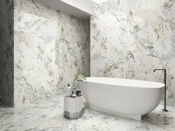 Łazienka wyłożona płytkami imitującymi marmur Alpen Quartz z białą wanną wolnostojącą