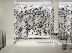 Łazienka wyłożona beżowymi płytkami imitującymi beton Raw Cotton oraz płytkami imitującymi marmur w kabinie prysznicowej, z podwójną umywalką ścienną i dużym lustrem