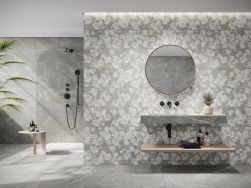 Łazienka wyłożona szarymi płytkami imitującymi kamień z kolekcji Augustus ze ścianką prysznicową, wiszącą umywalką i okrągłym lustrem