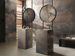 Łazienka ze ścianami wyłożonymi brązowymi płytkami imitującymi metal Reef Corten z dwiema stojącymi umywalkami i dwoma okrągłymi lustrami