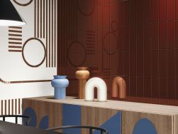 Ściana wyłożona płytkami z kolekcji Esencia Material oraz drewniana komoda z wazonami