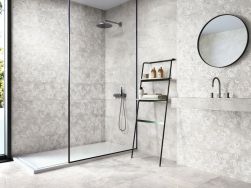 Łazienka wyłożona jasnymi płytkami imitującymi kamień z kolekcji Augustus z kabiną prysznicową, wiszącą umywalką, okrągłym lustrem i drabiną z kosmetykami