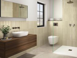 Łazienka wyłożona beżowymi cegiełkami ściennymi Acquarella Ivory z kabiną prysznicową, miską WC, ciemną szafką drewnianą z umywalką i lustrem