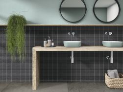 Łazienka wyłożona czarnymi cegiełkami ściennymi z kolekcji Pim Pam Pum z drewnianym stołem z dwiema umywalkami nablatowymi i dwoma okrągłymi lustrami
