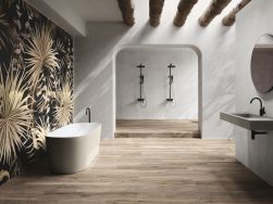 Łazienka ze ścianą wyłożoną dekoracyjnymi płytkami w brązowe liście z kolekcji Atelier z wanną wolnostojącą, wiszącą umywalką, okrągłym lustrem i prysznicem we wnęce