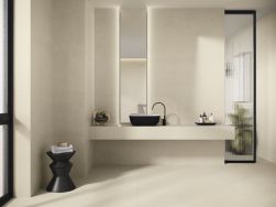 Łazienka wyłożona beżowymi płytkami imitującymi beton Raw Toasted Smooth z wiszącą p&oacute;łką z czarną umywalką nablatową, wąskim lustrem i czarnym taboretem