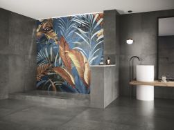 Łazienka wyłożona szarymi płytkami oraz ścianą z prysznicem wyłożoną dekoracyjnymi płytkami w egzotyczne wzory z kolekcji Atelier z umywalką stojącą, blatem i długim lustrem