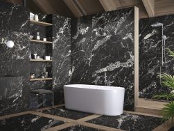 Łazienka wyłożona czarnymi płytkami imitującymi marmur Black Hispania z białą wanną wolnostojącą, półkami w ścianie i prysznicem