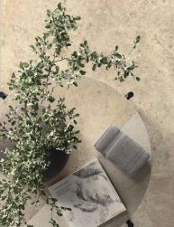 Zdjęcie przedstawia stylową aranżację na okrągłym stoliku kawowym, łączącą elementy natury i design
