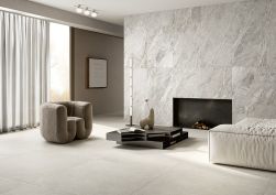 Beżowe płytki podłogowe The Blend od Fioranese na podłodze w salonie w połączeniu z szarym marmurem na ścianie
