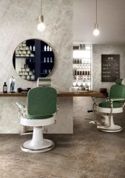 Salon fryzjerski w płytkach brązowych imitujących kwarcyt i beżowymi na ścianach, zielono białym fotelem