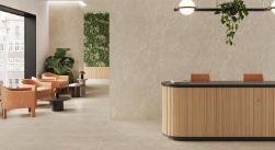 Wizualizacja nowoczesnego lobby wykończonego płytkami Lithos Sand imitującymi kamień. Wnętrze z lamelową recepcją, rudymi fotelami, czarnymi stolikami oraz zieloną ścianą z roślinnością.