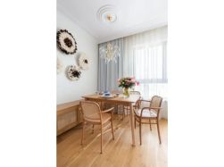 Jasny salon w stylu boho chic z drewnianym stołem i krzesłami z plecionką wiedeńską.