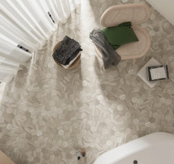 Łazienka, w rogu beżowe krzesło z poduszką i kocem, obok okrągły stolik, na podłodze płytki Lithos Beige 11,6x10,1 płytki heksagonalne