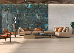 Salon, duża beżowa kanapa z dekoracyjnymi poduszkami, na podłodze płytki drewnopodobne, na ścianie płytki Geotiles Labradorite Blue Super Polished Rect. 60x120 płytki imitujące kamień