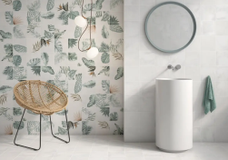 Wnętrze łazienki, biała umywalka wolnostojąca, okrągłe lustro na ścianie, ozdobny fotel, na ścianie płytki Geotiles Arnia Leaf Blanco 20,4x20,4 płytki z motywem roślinnym