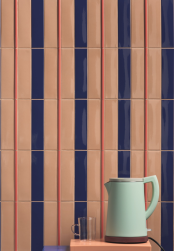 Na ścianie płytki z kolekcji Kappa, obok ściany stolik z czajnikiem, między płytkami Kappa Matita Berry 1,1x20 listwa dekoracyjna