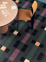 Pomieszczenie, na środku okrągły stół, na stole rozrzucone karty, przy stole krzesło, na podłodze płytki Pixel41 37 Military 11,55x11,55 płytka dekoracyjna