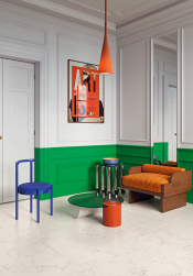 Pokój dzienny, przy ścianie kanapa w pomarańczowym kolorze, obok stolik i krzesło w niebieskim kolorze, ściana w kolorze biało-zielonym, lampa w kolorze pomarańczowym, na podłodze płytki Superclassica SCW Honed 60x60 płytki imitujące kamień
