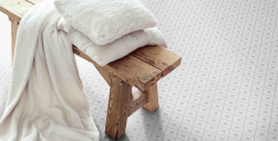 Drewniana krzesło, na krześle poduszki i koc w białym kolorze, na podłodze płytki Alhambra Gris 25x25 płytki patchworkowe