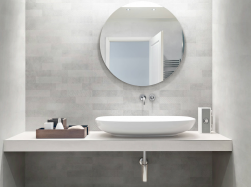 Łazienka, na blacie umywalka, obok akcesoria łazienkowe, na ścianie okrągłe lustro, ściana wyłożona Carpi Decorado Gris 20x50 płytka imitująca beton