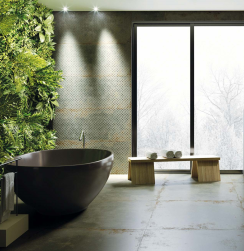 Łazienka, czarna wanna wolnostojąca, duże okno, przy oknie drewniana ławka z ręcznikami, ściana przy wannie wyłożona dekoracyjnymi, na podłodze Flamed Green Natural Rect. 99,55x99,55 płytki imitujące metal