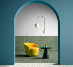 Poczekalnia, żółty fotel, zielony okrągły stolik, na połowie ściany i na podłodze położone Terrazzo Green Natural 59,2x59,2 płytka imitująca lastryko