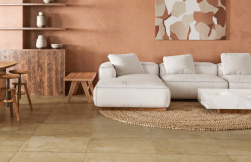 Salon, ściana w brązowym kolorze, biała kanapa, brązowe meble, na podłodze Terracota Siena Natural 50x100 płytka imitująca beton